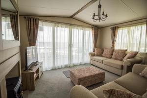 a living room with a couch and a tv at Beautiful Caravan With Stunning Sea Views At Haven Hopton Ref 80001h in Great Yarmouth