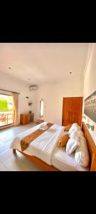 um quarto com uma cama grande com lençóis brancos e almofadas em Villa Seruni Lovina em Lovina
