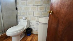 a bathroom with a toilet and a wooden door at Cabañas Manuto in Hanga Roa