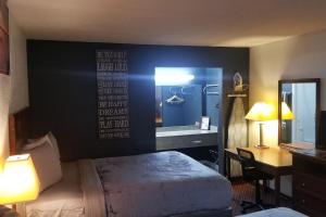 ein Hotelzimmer mit einem Bett, einem Schreibtisch und einem Spiegel in der Unterkunft OSU 2 Queen Beds Hotel Room 230 Wi-Fi Hot Tub Booking in Stillwater