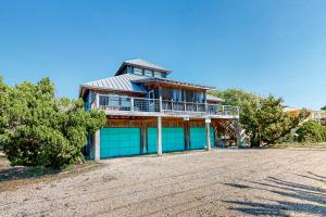 a large blue house with a balcony on a dirt road at Knot Too Shabby in St. George Island