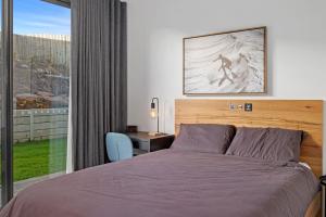 a bedroom with a bed and a large window at Amongst The Tea Trees in Inverloch