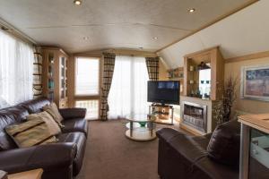 a living room with a leather couch and a television at Luxury Caravan For Hire At Hopton Holiday Park With Full Sea Views Ref 80010h in Great Yarmouth