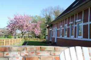 a house with a brick wall and a tree with pink flowers at Ferienwohnung GeestZuhause in Heeslingen