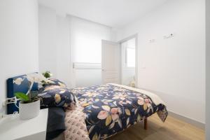una camera da letto con un letto con copriletto floreale di Apartamentos La Gringa Centro Gijon II Obra nueva con posibilidad de Parking a Gijón