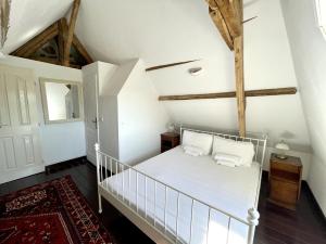 - une chambre dotée d'un lit avec des draps blancs et des poutres en bois dans l'établissement Le Mirador - Splendide vue sur la Roque-Gageac, à Vézac