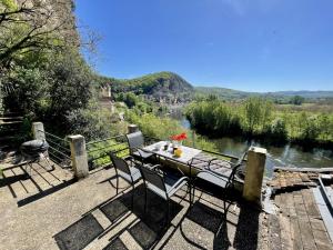 una mesa y sillas en una terraza con vistas al río en Le Mirador - Splendide vue sur la Roque-Gageac en Vézac