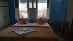 Habitación azul con 2 camas con almohadas de color naranja en Sri Yoga Mandir, en Varanasi