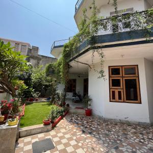 a white house with a courtyard with potted plants at Travel curiosity Homestay in Alwar