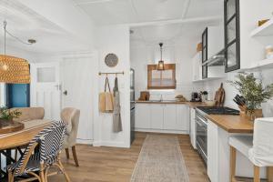 une cuisine avec des placards blancs, une table et une salle à manger dans l'établissement Bryony Cottage Berrima, à Berrima