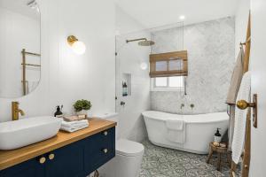 a bathroom with a tub and a toilet and a sink at Bryony Cottage Berrima in Berrima