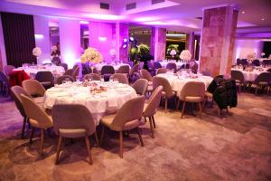 a banquet room with tables and chairs and purple lighting at Oaza Hotel in Štip