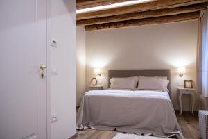 a bedroom with a white bed with a wooden ceiling at Alloggi I Calieroni in Valstagna