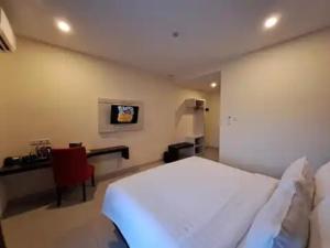 Hotel Simfony Alor في Kalabahi: غرفة نوم بسرير ابيض ومكتب