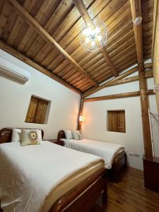 2 Betten in einem Zimmer mit Holzdecken und einem Kronleuchter in der Unterkunft 芹壁小玖窩民宿 in Beigan