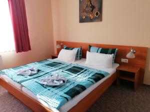 ein Bett mit einer blauen Decke und zwei Handtüchern darauf in der Unterkunft Hotel Garni zum Goldenen Ring in Quedlinburg