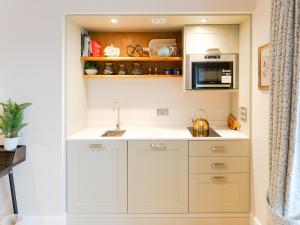 una cocina con armarios blancos y fregadero en Cuillin Studio - Ukc6562, en Mallaig
