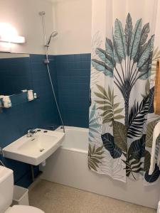 a bathroom with a sink and a shower curtain at Hotel Le Cosy Riva Bella in Ouistreham