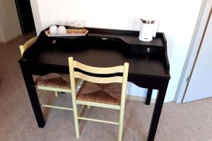einen schwarzen Schreibtisch mit einem Stuhl und einer Tastatur in der Unterkunft L'Annexe in Môtiers