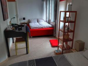 a living room with a red couch and a desk at L'Annexe in Môtiers