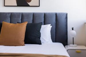 a bedroom with a bed with a blue headboard and pillows at The Horizon Apartments by Urban Rest in Sydney
