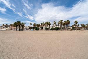 a sandy beach with palm trees in the distance at BF Rooms Carboneras in Carboneras