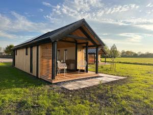 a small cabin with two chairs in a field at Gastenverblijf De Natureluur in Noorden