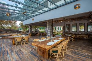 a restaurant with wooden tables and chairs on a wooden floor at The Riverwood Forest Retreat - Kanha in Kānha