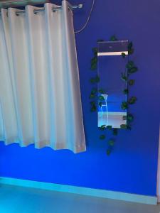 a blue room with a white curtain and a mirror at Casa Felice Jonak in Jorhāt