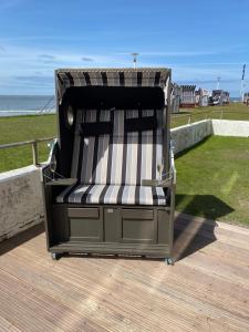 a beach chair sitting on a deck near the ocean at Weststrandperle in Norderney