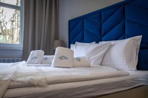 Apart-Invest Apartament Latte في شكلارسكا بوريبا: سرير كبير مع وسائد بيضاء و اللوح الأمامي الأزرق