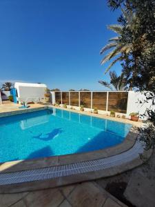 a swimming pool in a resort with a clear blue sky at Dar Lagune Djerba in Al Ḩaddādah
