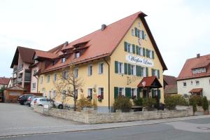Burgthann的住宿－Weißer Löwe，街上有红色屋顶的黄色建筑