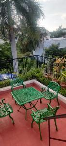 a patio with three green benches and a table at Coralshelters Kochadai in Madurai