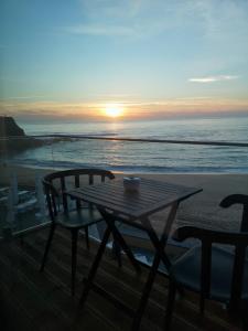 uma mesa e cadeiras na praia com o pôr do sol em Promar - Eco Beach & Spa Hotel em Maceira