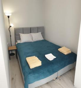 a small bedroom with a blue bed with towels on it at Apartamenty Katowice Chopina 16 in Katowice
