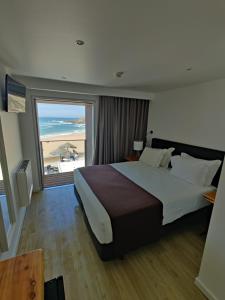 a bedroom with a large bed and a large window at Promar - Eco Beach & Spa Hotel in Maceira