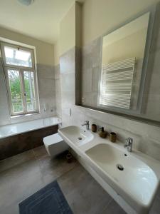 ein weißes Badezimmer mit einem Waschbecken und einem Spiegel in der Unterkunft Ruhige&charmante Altbauwohnung in Leipzig