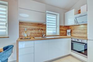 uma cozinha com armários brancos e um lavatório em Apartments Birimac em Pula