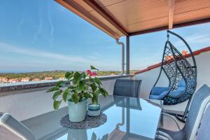 a balcony with a glass table and chairs and a swing at Apartments Birimac in Pula