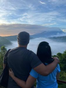 a man and a woman standing on top of a mountain at pinggan sunrise glamping in Baturaja