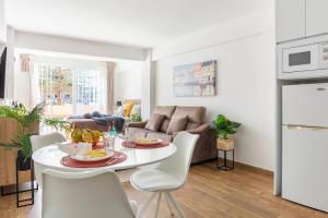 una cucina e un soggiorno con tavolo e sedie bianchi di Serenity Chic Apartment City Center with FREE Wifi BY NAMASTE ELITE a Torremolinos