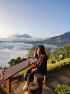 Baturaja的住宿－pinggan sunrise glamping，坐在长椅上看着风景的女人