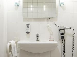 Baño blanco con lavabo y espejo en ibis Stuttgart Centrum, en Stuttgart