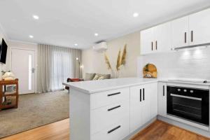 a kitchen with white cabinets and a living room at Terra Mare in Geelong West