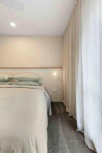 um quarto com uma grande cama branca e cortinas em Terra Mare em Geelong West