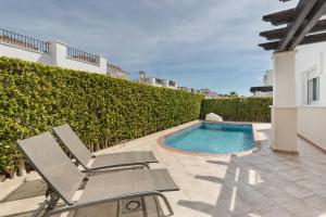 um pátio com uma piscina, 2 cadeiras e uma piscina em Casadeluxe Villa La Torre Lenguado em Torre-Pacheco