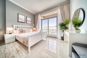 a bedroom with a white bed and a large window at Elegant Studio at Al Madar Siraj Tower 1 Al Barsha South by Deluxe Holiday Homes in Dubai