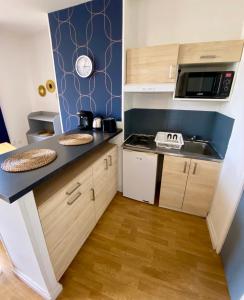 eine kleine Küche mit einer Spüle und einer Mikrowelle in der Unterkunft La Vague Dorée - Hyper-Centre - 15 min de Rouen in Barentin