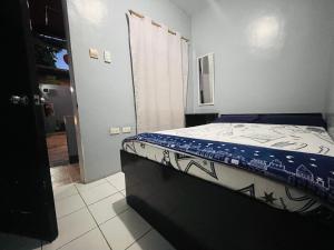 a bedroom with a bed with a blue and white comforter at Danao LC Bayview in Idanao